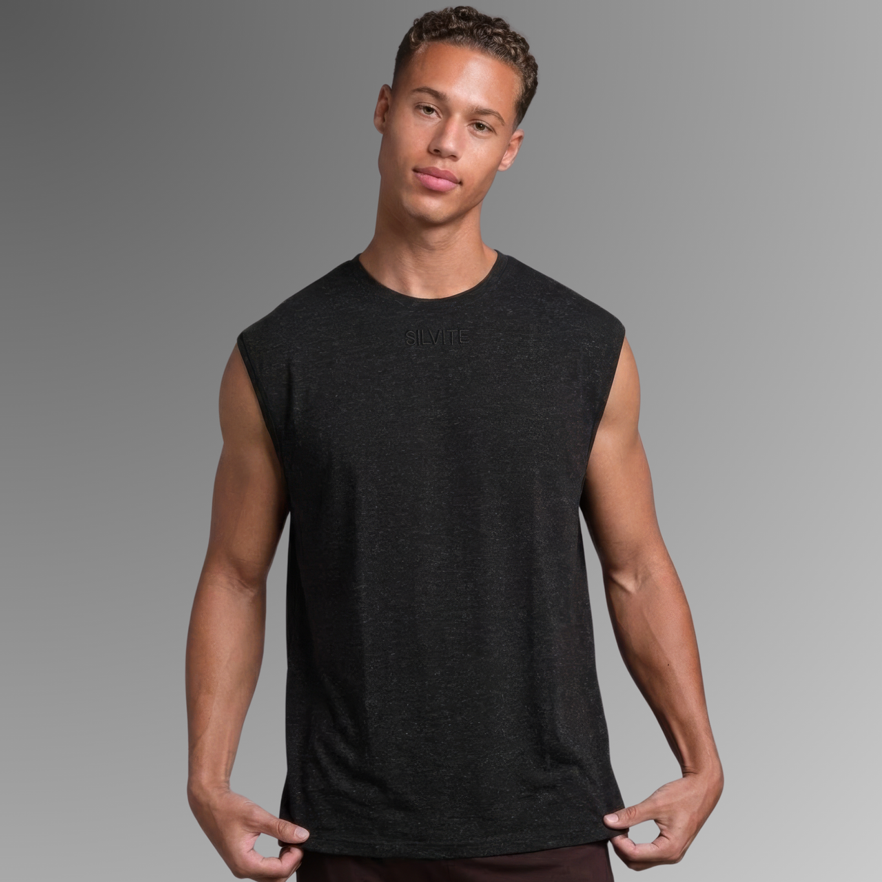 A man wearing a dark charcoal antibacterial sleeveless crewneck pyjama top, standing against a neutral gray gradient background.