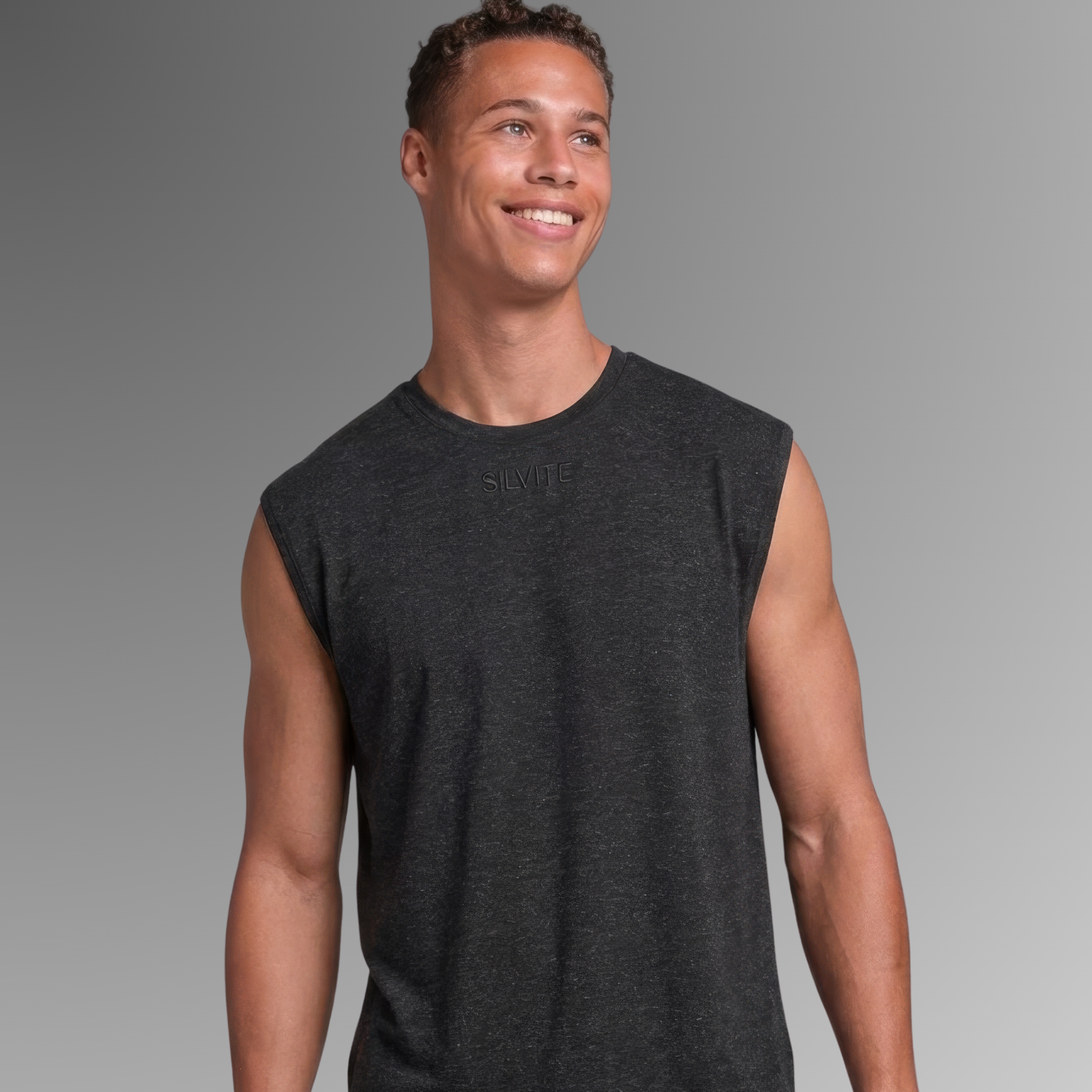 A man wearing a dark charcoal gray antibacterial sleeveless pyjama t-shirt, shown from the waist up against a neutral gray gradient background.